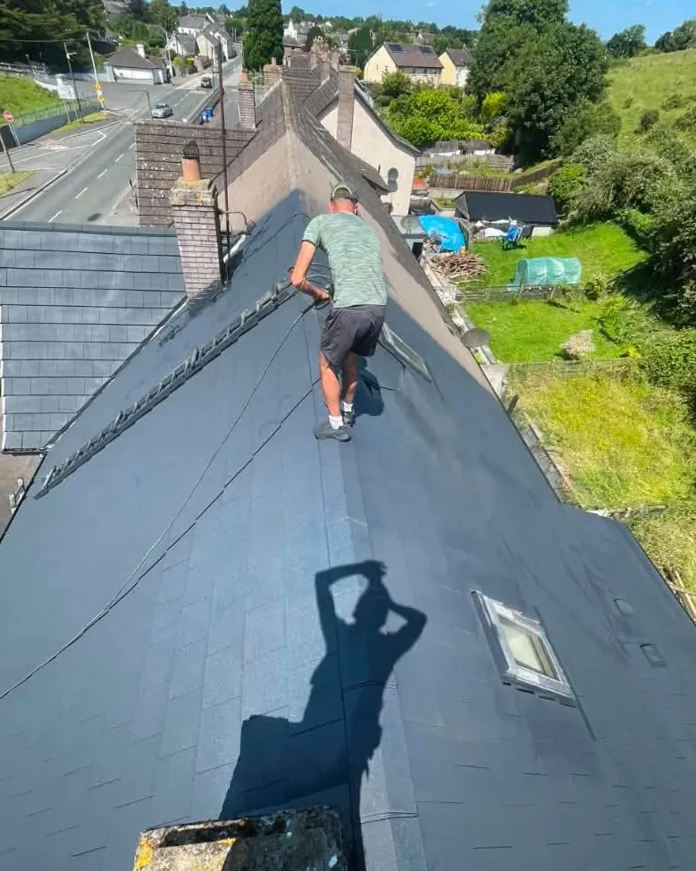 Worker soft washing a slate roof on a County Kilkenny home